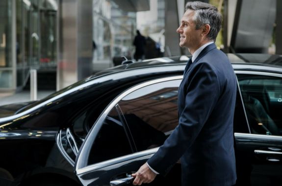 Experienced chauffeur opening luxury car door for business clients in Valley Center Ca.